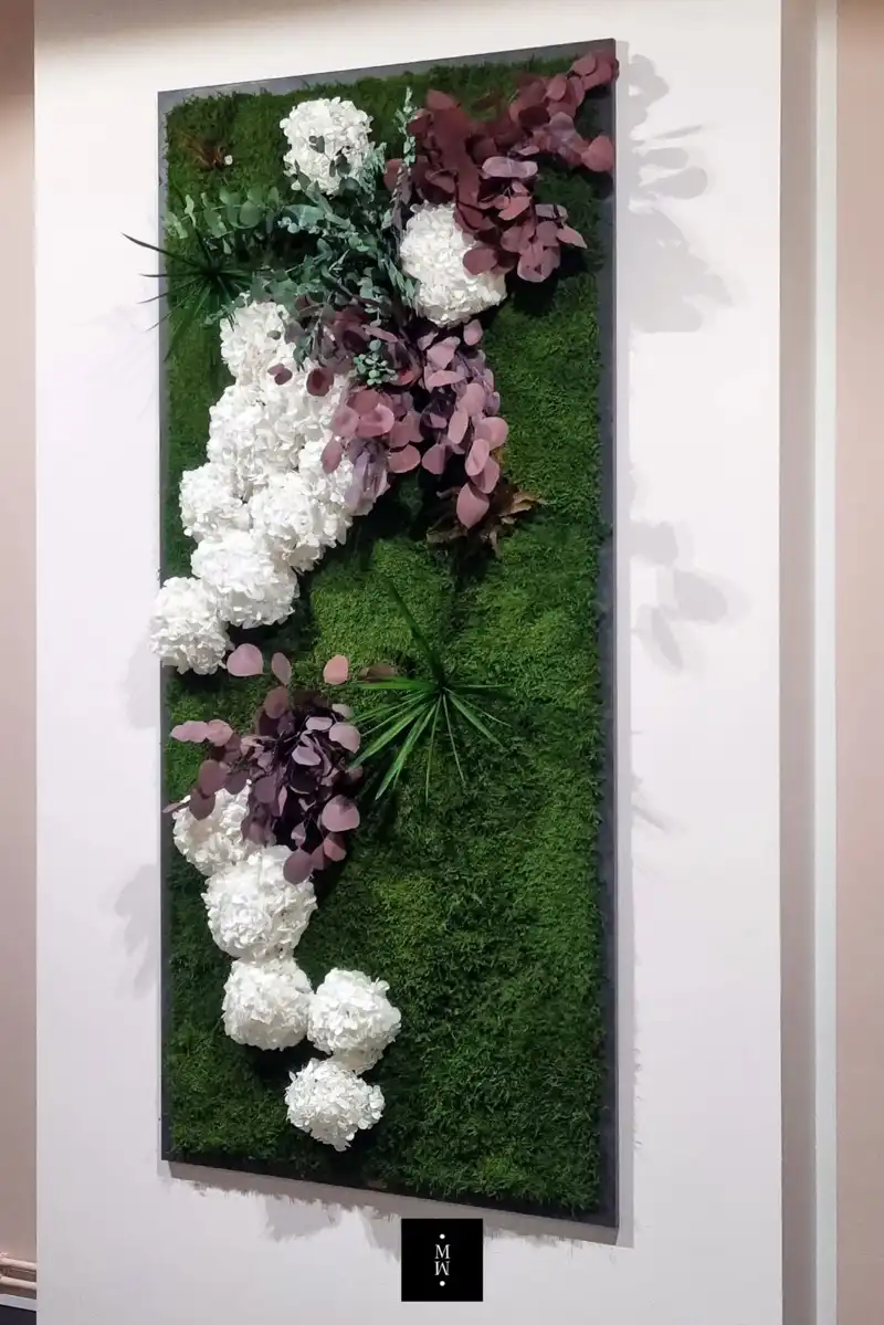 a wall with white flowers and green leaves