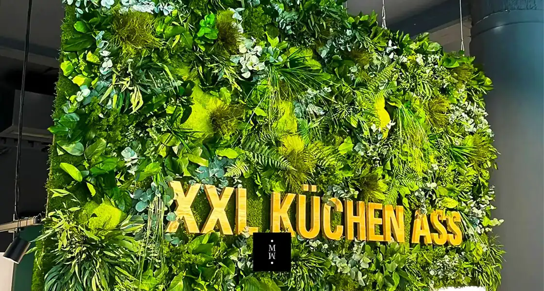 a wall of plants with gold letters