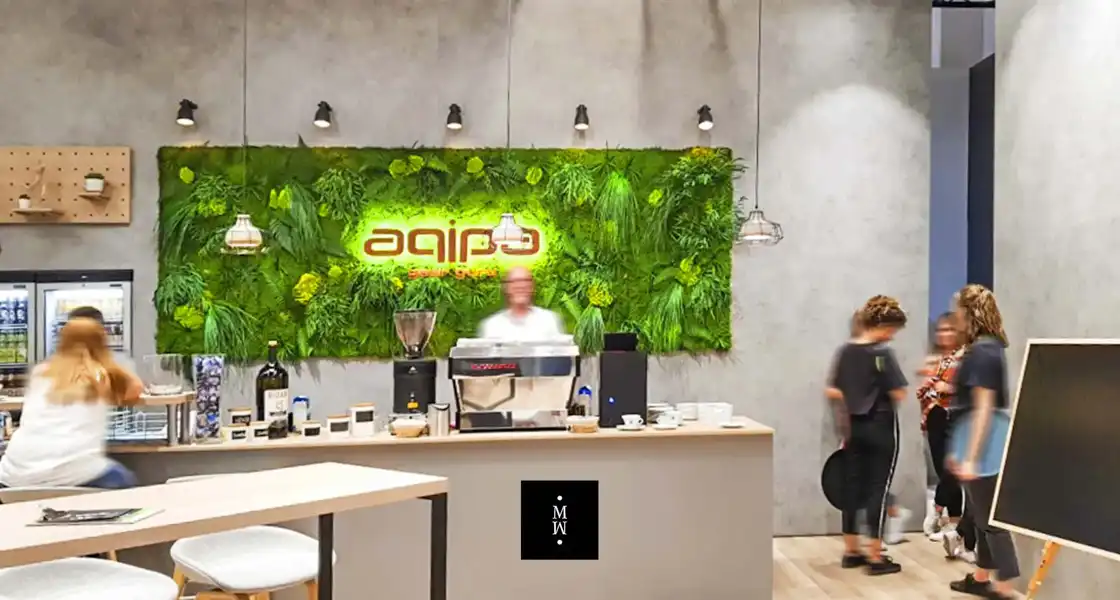 a man standing behind a counter in a room with plants