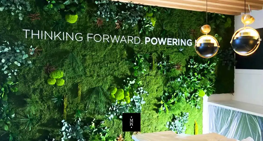 a green wall with plants and a lamp