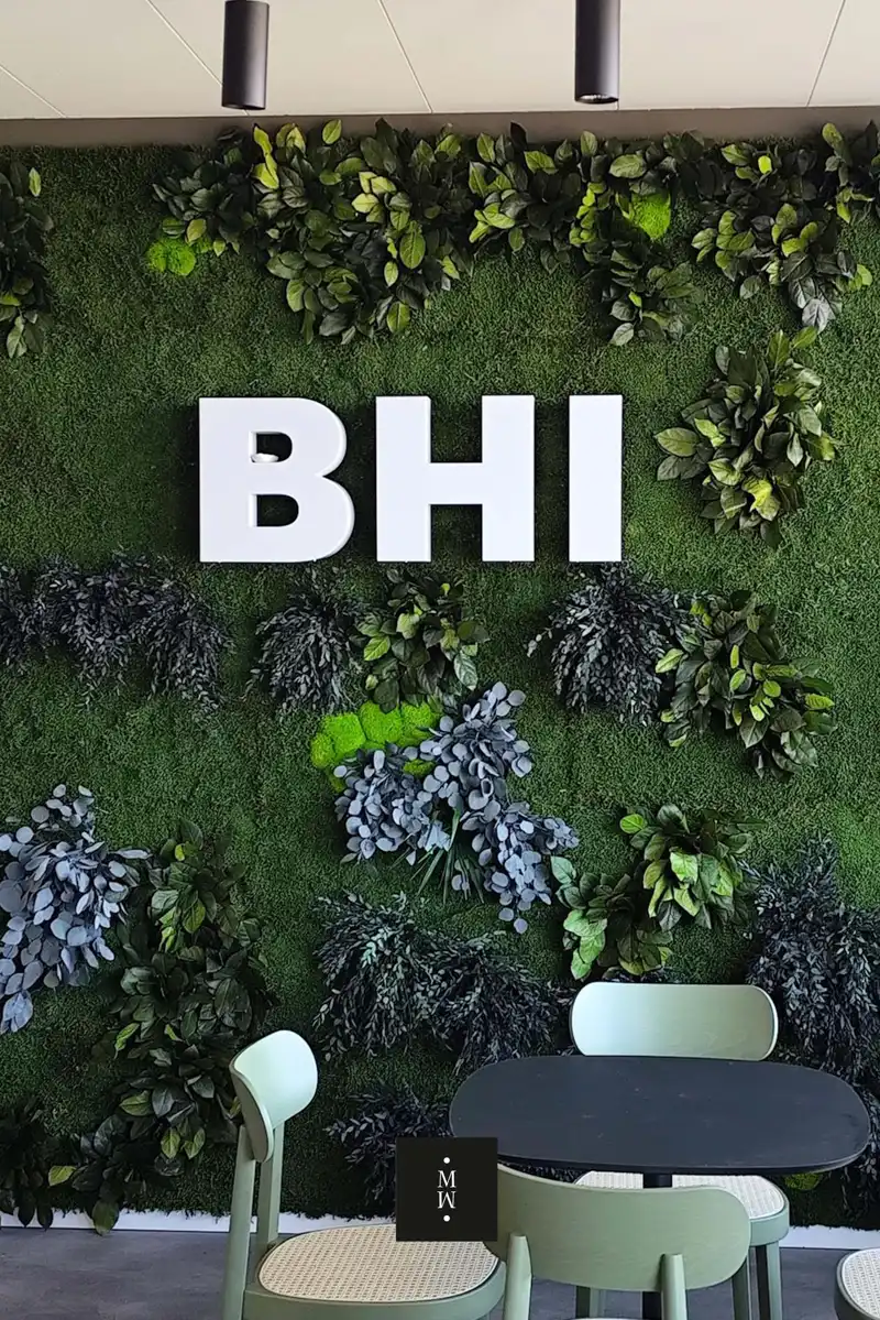 a white letters on a green wall with plants