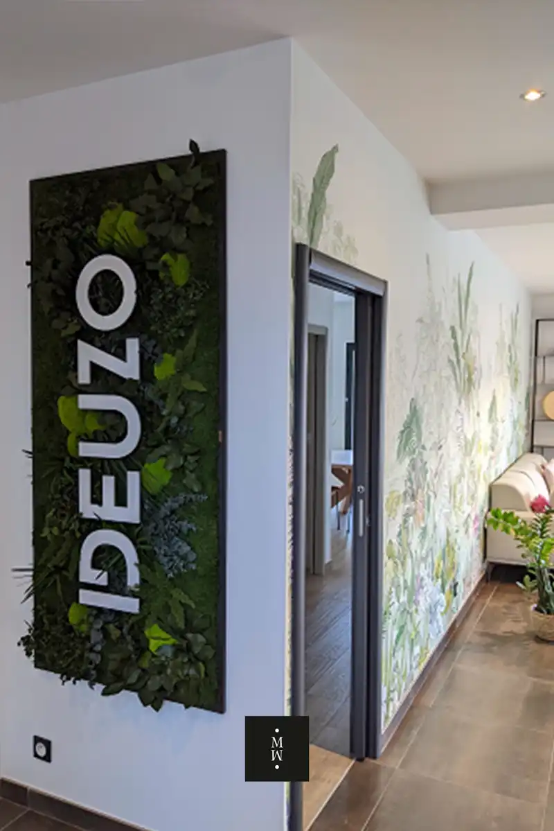 a sign on a wall with plants on it