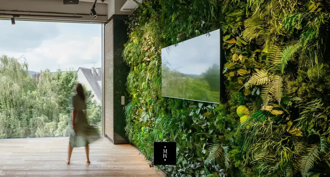 a woman walking in front of a wall of plants