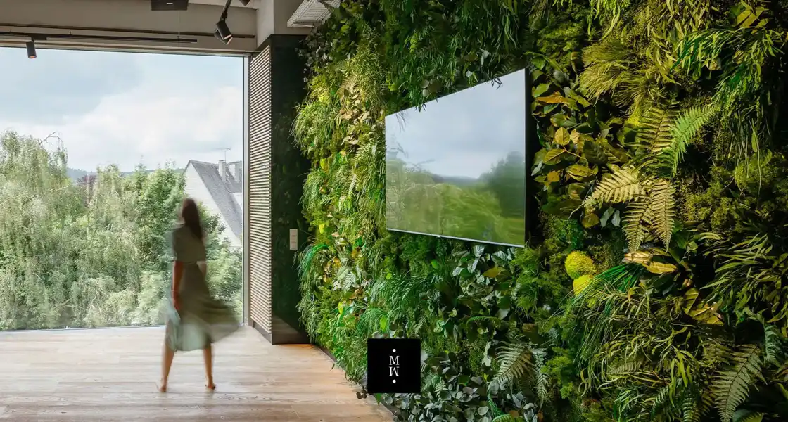 a woman walking in front of a wall of plants