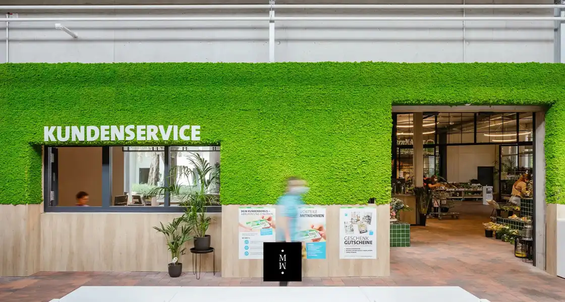 a green wall with a person walking in front of it