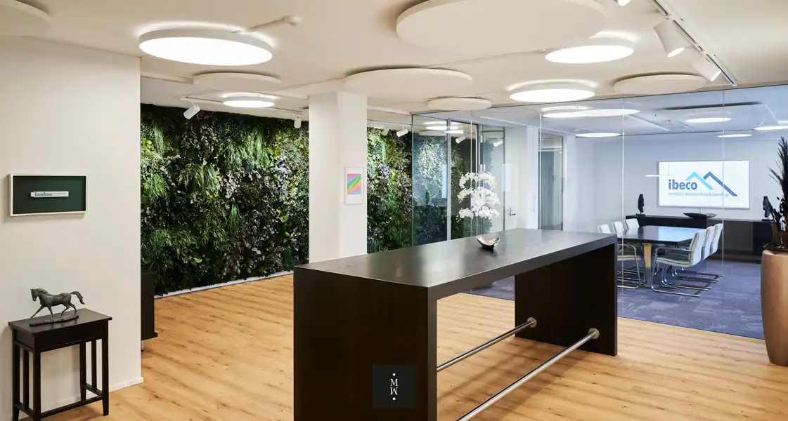 a room with a long table and plants on the wall