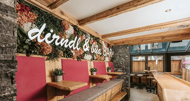 Bild aus Moos mit Blumen-Elementen und Schriftzug „dirndl & bua BAR“, gestaltet von Moosmoos.