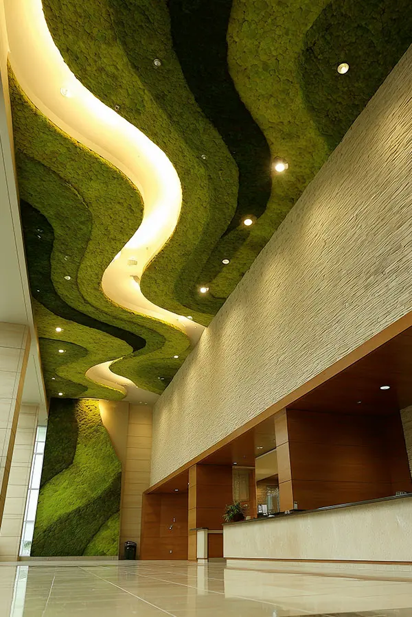 Organisch geschwungene MoosMoos Decke aus Moos in einer hohen Hotel Lobby mit stilvoller Rezeption.