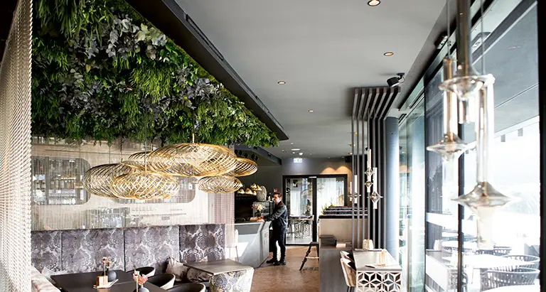 Restaurant mit stilvoller Decke aus Dschungelmoos von MoosMoos, kombiniert mit modernen Lampen und eleganter Einrichtung