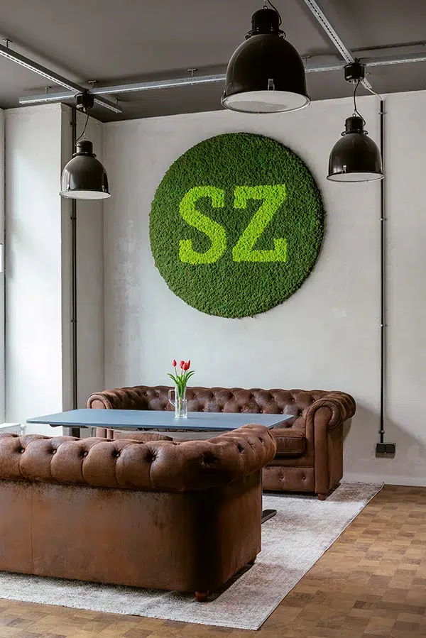 Runde MoosMoos Wand aus Moos mit integriertem Firmenlogo – modernes grünes Design für Büroräume und Lounges.