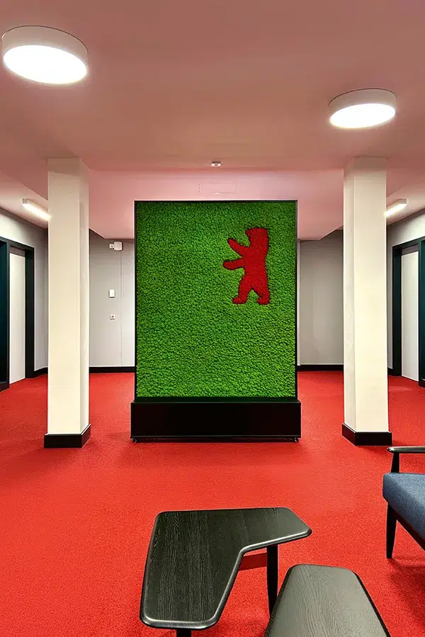 Kreative MoosMoos Wand aus Moos mit integriertem Berliner Bär Logo – grüne Markeninszenierung für Büro- und Empfangsbereiche.
