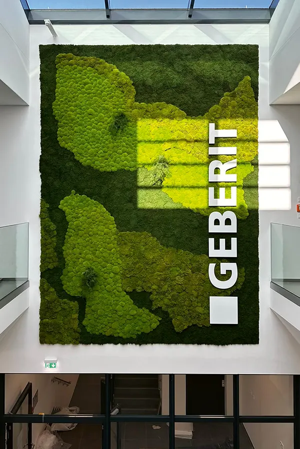 Nachhaltige MoosMoos Wand aus Moos mit Firmenlogo von Geberit – natürliche Markenpräsentation für Innenarchitektur und Empfangshallen.