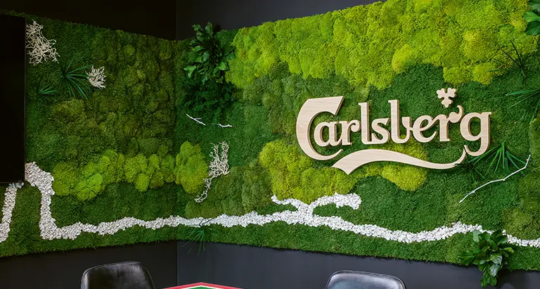 Individuelle MoosMoos Wand aus Moos mit integriertem Carlsberg Logo – grünes Corporate Design mit Naturmaterialien.