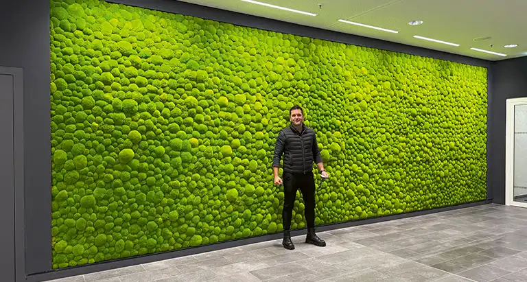 Großflächige Wand aus Ballenmoos von MoosMoos in einem öffentlichen Gebäude, nachhaltiges Naturdesign, mit Person im Vordergrund