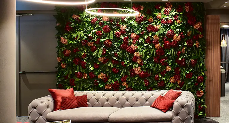 Elegante Wand aus Moos mit roten Blumenakzenten im Wohnzimmer – kreative MoosMoos Mooswand für luxuriöse Innenräume.