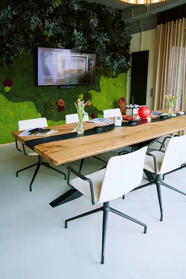 Besprechungsraum mit großem Tisch, Stühlen, Bildschirm und dekorativer Wand aus Moos von MoosMoos, nachhaltiges Raumkonzept für Büros