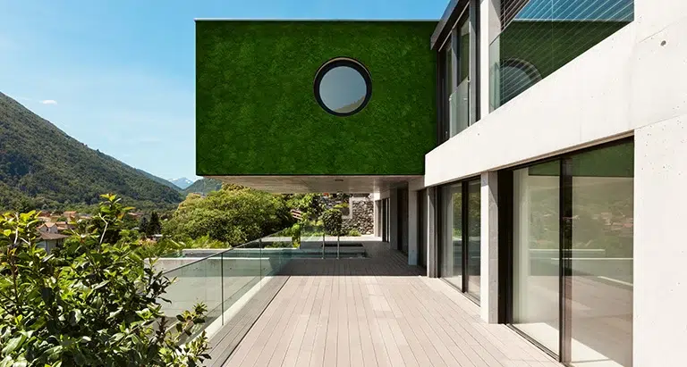 Moderne Villa mit Waldmoos-Mooswand und Rundfenster – nachhaltige Greenovation Gebäudebegrünung mit Aussicht