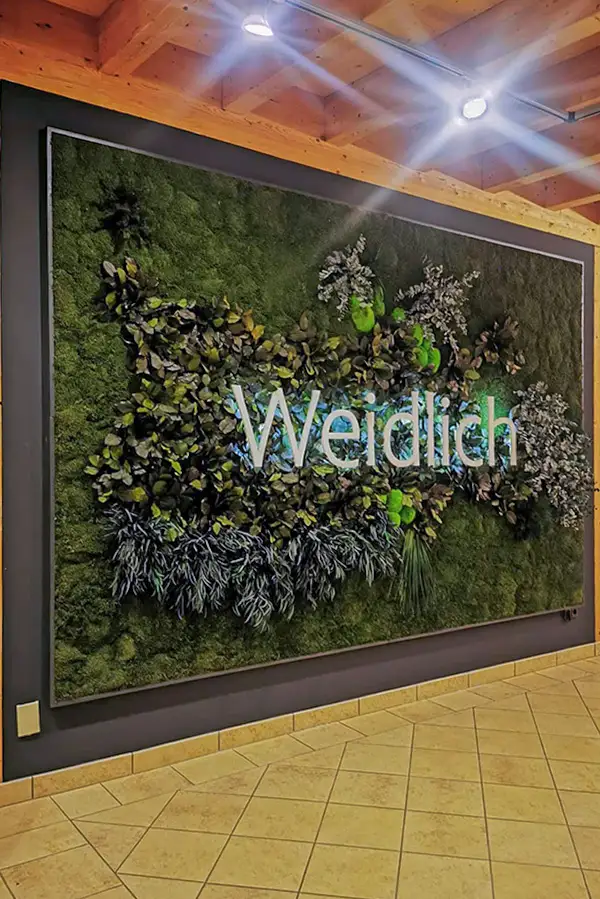 Mooswand mit Weidlich-Logo und floralen Akzenten im Innenraum